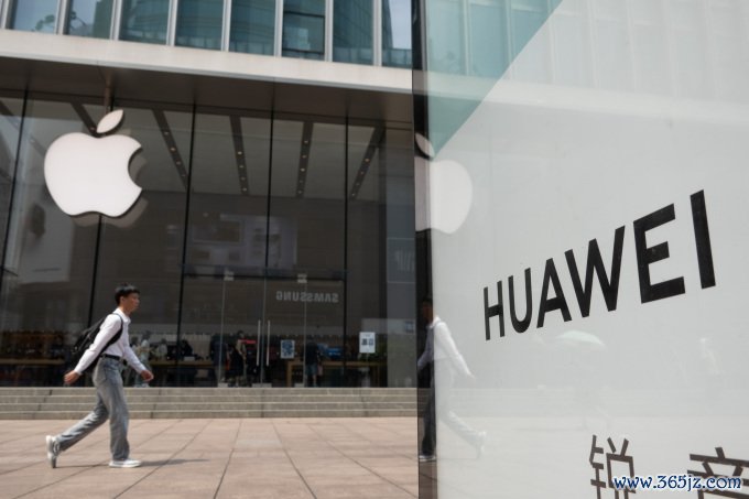 Một người đi ngang Apple Store ở Thượng Hải， phía trước là biển quảng cáo Huawei. Ảnh: Reuters